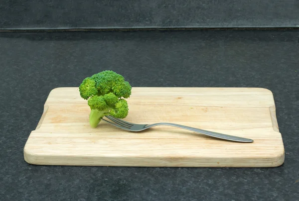 Verse groene groenten. Broccoli met een vork op een snijplank — Stockfoto