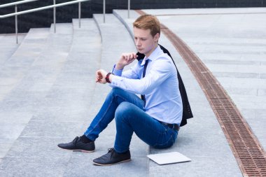 Saat bakarak ve istemci için bekleyen genç işadamı