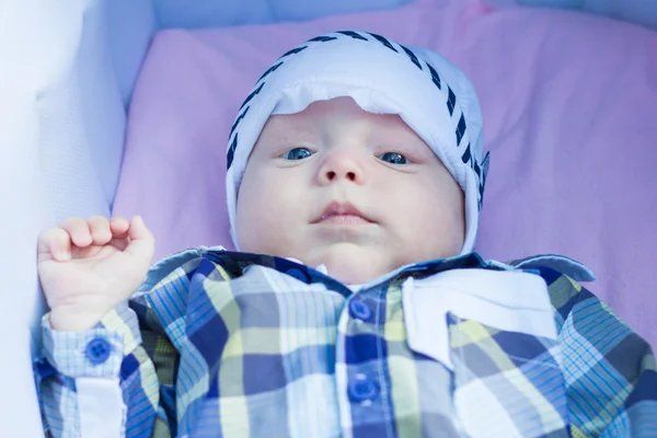 Bebé de seis meses está acostado en un cochecito y mira a su alrededor —  Fotos de Stock
