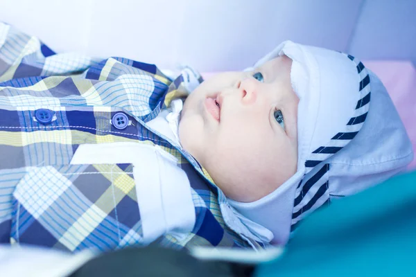 Bebé de seis meses está acostado en un cochecito y mira a su alrededor — Foto de Stock