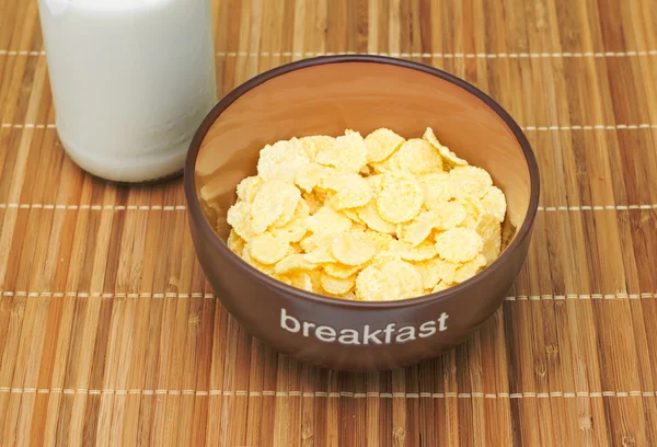 Cuenco con hojuelas crujientes con leche en un mantel de bambú. Desayuno . —  Fotos de Stock