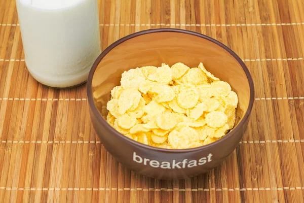 Cuenco con hojuelas crujientes con leche en un mantel de bambú. Desayuno . —  Fotos de Stock