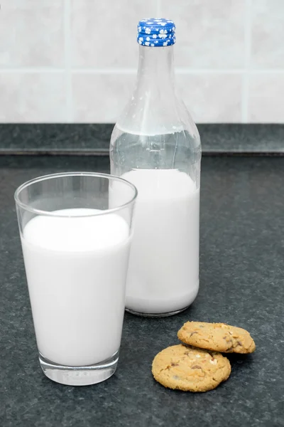 Botella de leche, un vaso de leche y galletas sobre la mesa —  Fotos de Stock