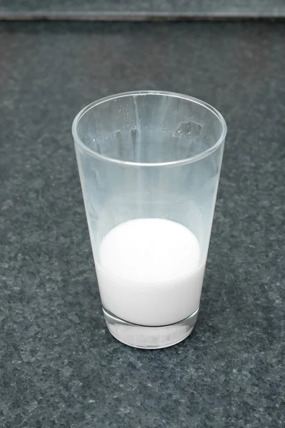 Vaso de leche sin terminar sobre la mesa —  Fotos de Stock