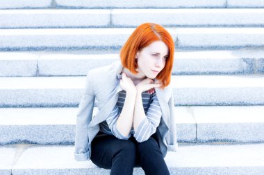 Kızıl saçlı güzel genç kadın merdiven üzerinde oturan bir ceket ile
