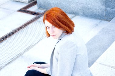 Kızıl saçlı güzel genç kadın merdiven üzerinde oturan bir ceket ile