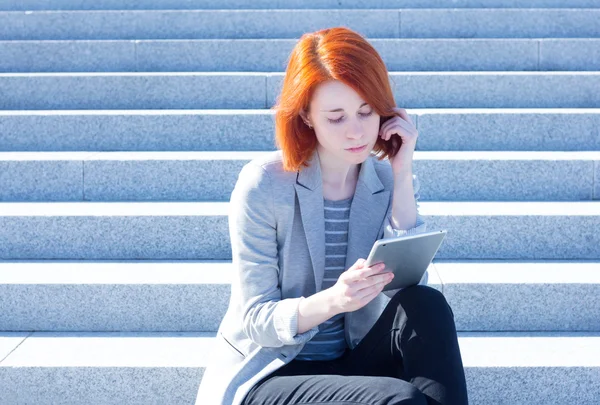 Kvinna sitter på trappan på gatan och arbetar på en Tablet PC — Stockfoto