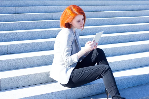 Woman sitting on the stairs on the street and working on a tablet — Stock Photo, Image