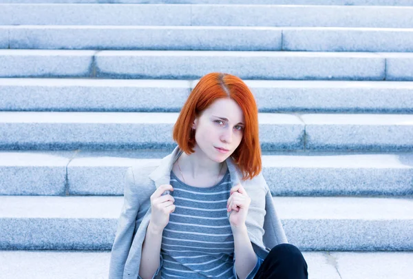 Redhead mooie jonge zakenvrouw met een jas zittend op t — Stockfoto