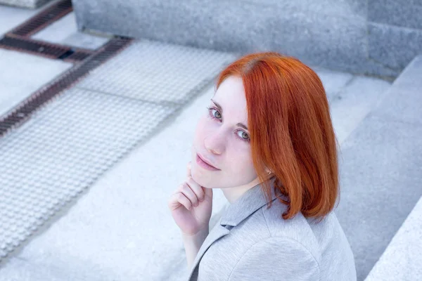 Portret van roodharige zakenvrouw met glimlach buiten zitten op de trap — Stockfoto