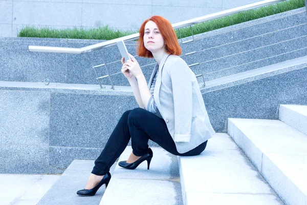 Mujer de negocios sentada en la calle con una tableta en un día soleado —  Fotos de Stock