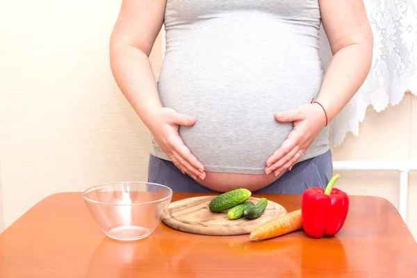 Terhes nő és zöldség az asztalon. Diéta a terhes nők számára. — Stock Fotó