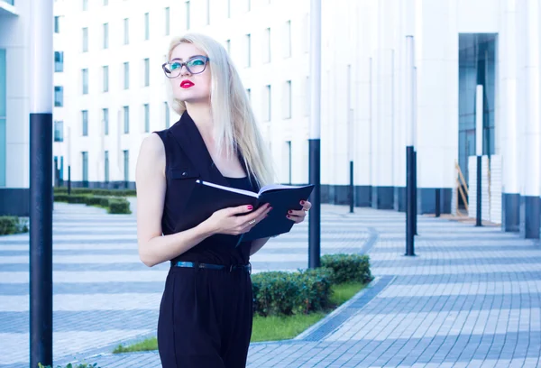 Biznes kobieta z notebookiem patrząc do odległości na tle centrum biznesowego — Zdjęcie stockowe