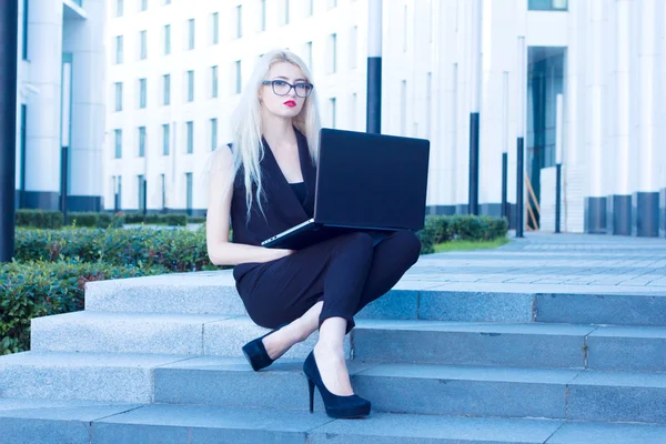 Business blondin med röda läppar sitter och arbetar med laptop — Stockfoto