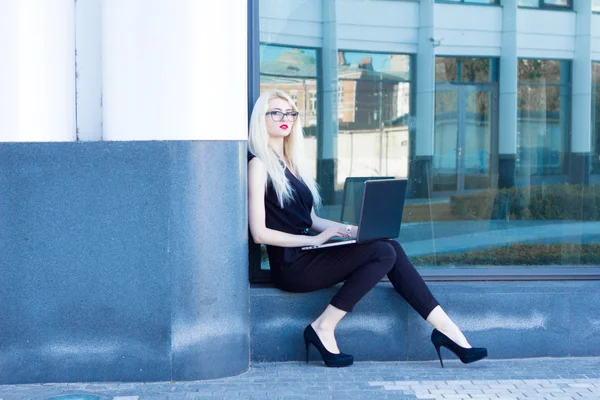 Επιχείρηση ξανθιά με κόκκινα χείλη, κάθεται και εργάζεται με laptop — Φωτογραφία Αρχείου