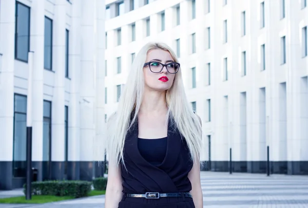 Retrato de una mujer rubia inteligente en el fondo del centro de negocios —  Fotos de Stock