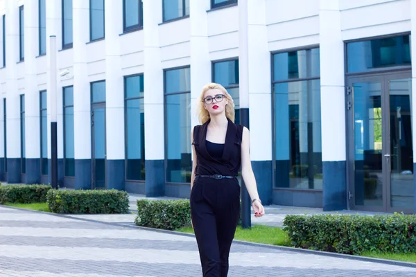 Mujer inteligente camina por la calle contra el fondo del centro de negocios —  Fotos de Stock