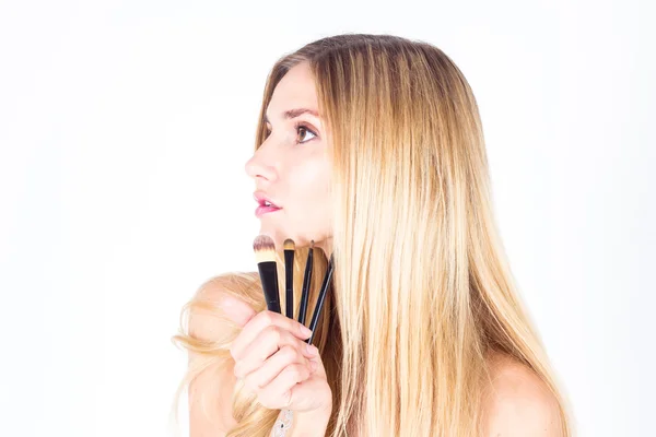 Jovem mulher está segurando escovas cosméticas. Maquilhagem — Fotografia de Stock