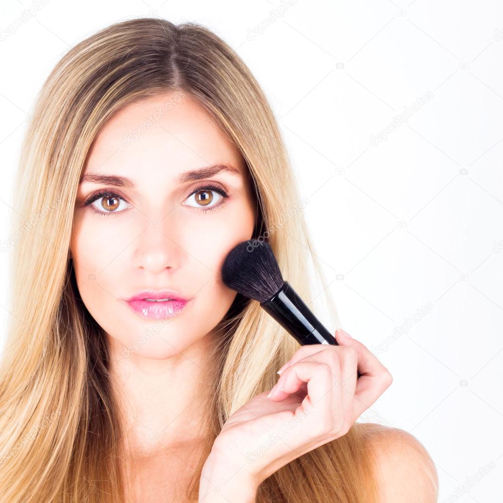 Woman with make-up and brush for rouge. Close up