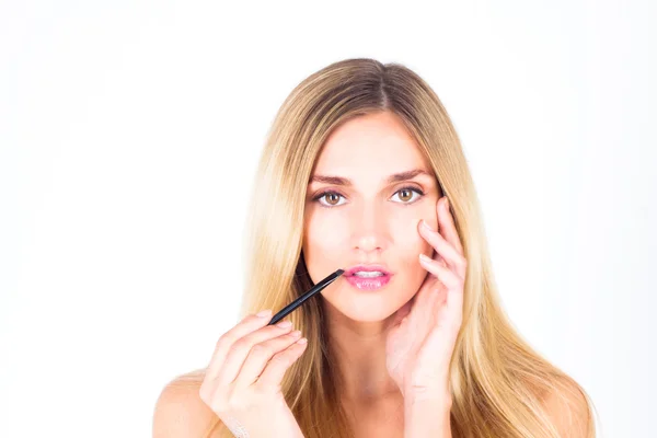 Beautiful woman applying shine on her lips with a brush and touching her face — Stock Photo, Image