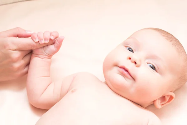 Annenin parmak tutarak ve gülümseyen 2 aylık bebek