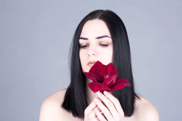 Face of a woman with eyes closed and red flower. Beauty treatment concept.