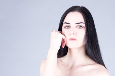 Yanağı el ile dokunmak ve kameraya bakarak genç, güzel esmer