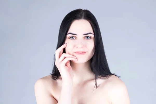 Femme aux cheveux foncés souriant et touchant sa joue à la main. Concept de beauté — Photo