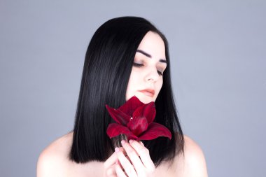 Güzel kadın elinde kırmızı bir çiçek ile bakıyor