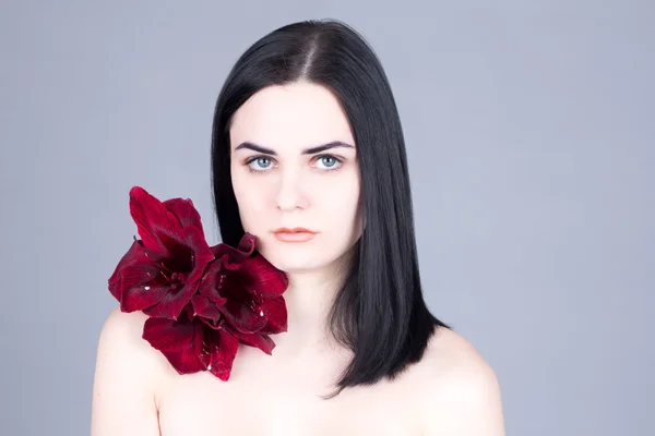 Vrouw met grote ogen en wit en met een bloem op haar schouder — Stockfoto