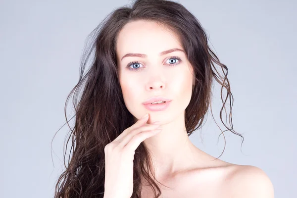 Belle jeune femme aux grands yeux bleus et aux cheveux bouclés touchant les lèvres. Beau visage de femme . — Photo