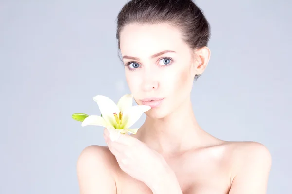 Mulher bonita com um lírio nas mãos e com grandes olhos azuis. SPA e beleza . — Fotografia de Stock