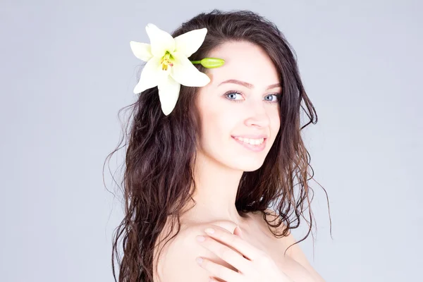 Όμορφη γυναίκα με λουλούδι στα σγουρά μαλλιά με ένα χαμόγελο με τα δόντια. Ομορφιά, περιποίηση προσώπου, Spa. — Φωτογραφία Αρχείου