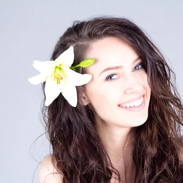 Femme riante avec fleur en cheveux bouclés avec sourire avec des dents. Traitement SPA . — Photo