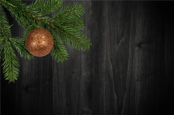 Ramo verde com bola de Natal no fundo de madeira — Fotografia de Stock