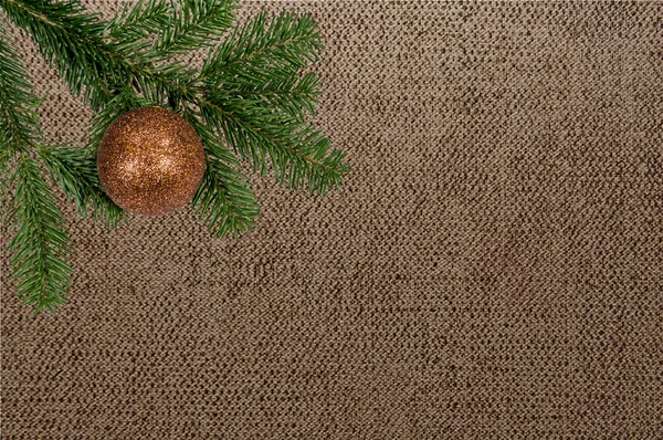 Grüner Zweig mit Weihnachtskugel auf Leinwand-Hintergrund — Stockfoto