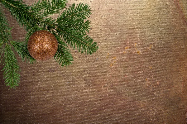 Grüner Zweig mit Weihnachtskugel auf Leinwand-Hintergrund — Stockfoto