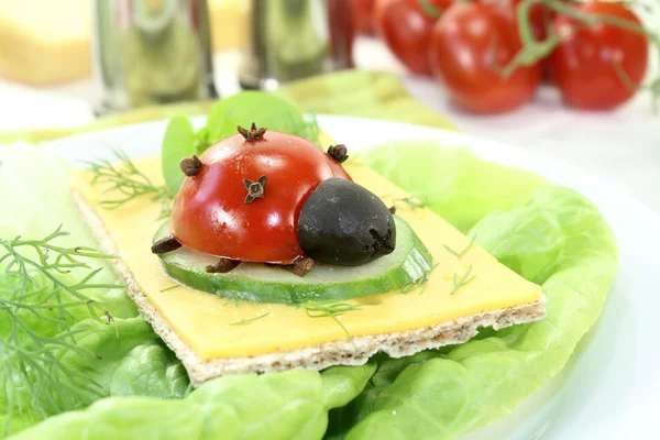 Crispbread with cheese, lettuce and ladybug — Stock Photo, Image