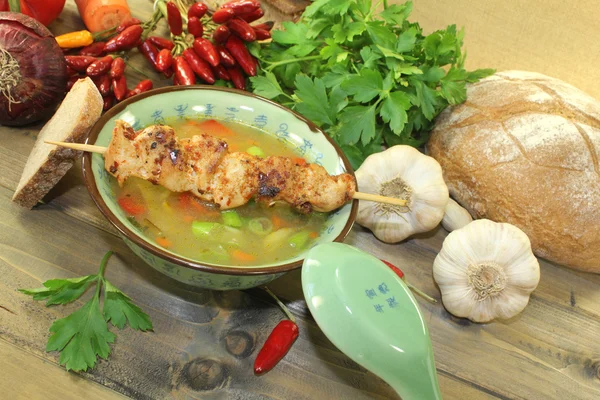 Poultry consomme with chicken skewer and greens — Stock Photo, Image