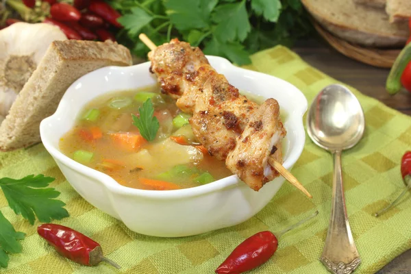 Geflügelconsomme mit Hühnerspießen und Petersilie Stockbild