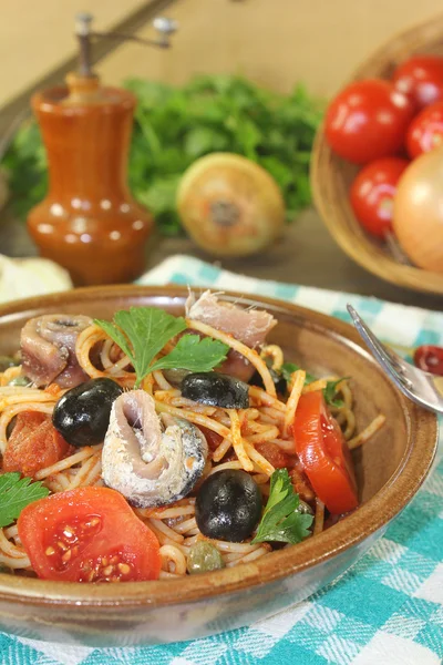 Spaghetti alla puttanesca mit Sardellen und Tomaten Stockbild