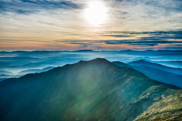 Sun and colorful clouds over hills — Stock Photo, Image