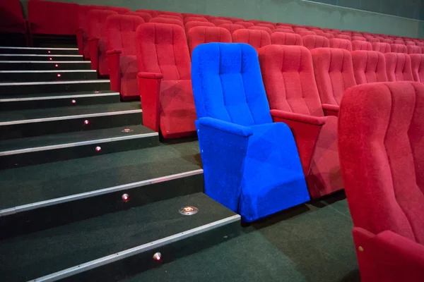 Blauwe stoel tussen rijen van rode stoelen — Stockfoto