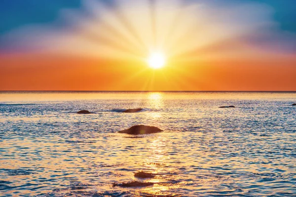 Sunset sea with rocks and evening sunset sun on dramatic sky