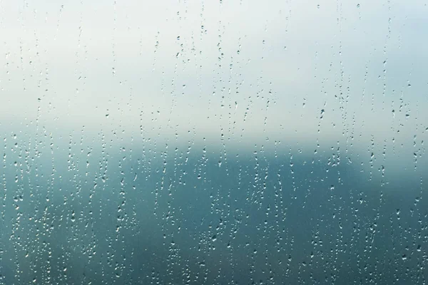 雨の水は青い窓ガラス表面にパターンをドロップ — ストック写真