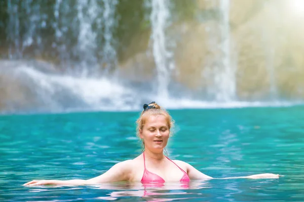 분홍색 비키니를 머리의 여자가 에메랄드 호수에서 폭포를 휴식을 취합니다 부리의에라 — 스톡 사진