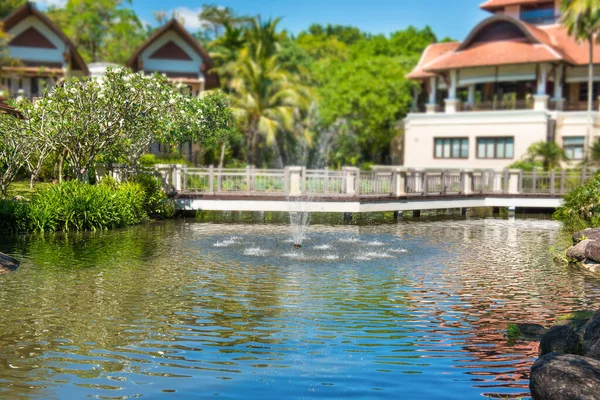 トロピカルリゾートの噴水と高級ホテルの建物がある美しい緑の池の景色 — ストック写真