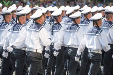 Askeri törenle yürüyen üniformalı askerler.