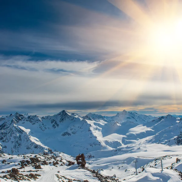 Sunset in snowy blue mountains with clouds — Stock Photo, Image