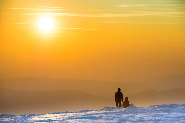 Les gens qui regardent le coucher du soleil dans les montagnes d'hiver — Photo